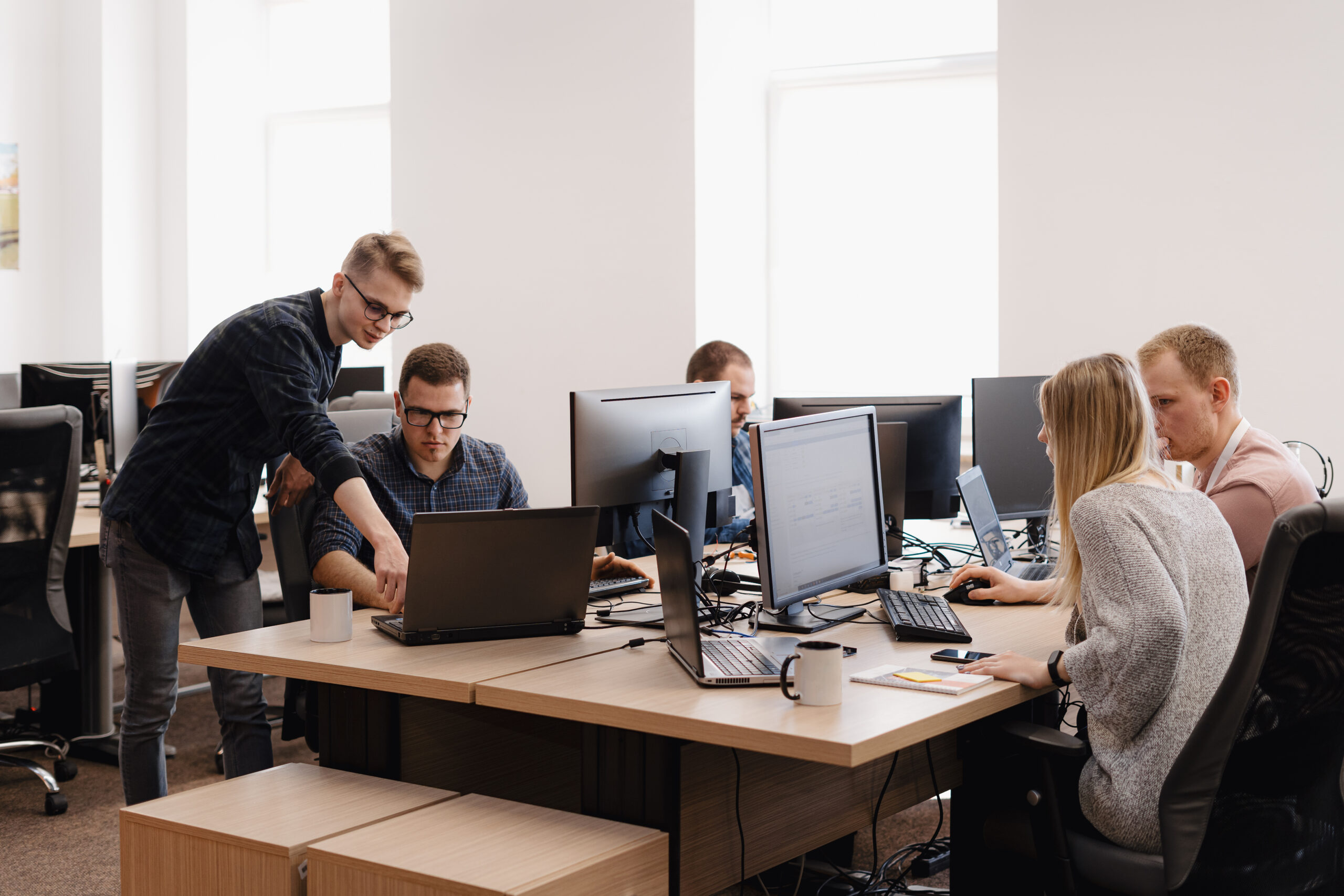 Full concentration at work. Group of young business people working and communicating while sitting at the office desk together with colleagues sitting in the background
